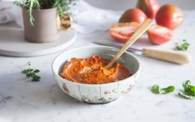 Skål med fyllig tomatbaserad sås och sked på marmorbänk