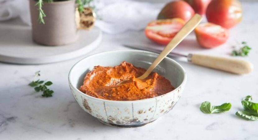 Skål med fyllig tomatbaserad sås och sked på marmorbänk